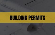 Text that says Building Permits on a light orange rectangle with construction plans in the background