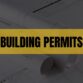 Text that says Building Permits on a light orange rectangle with construction plans in the background