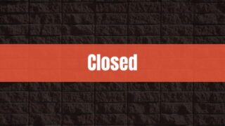 Text that says Closed on a red rectangle with a brick wall in the background.