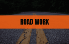 A two-lane road with double yellow lines, with an orange 'ROAD WORK' banner across the center.