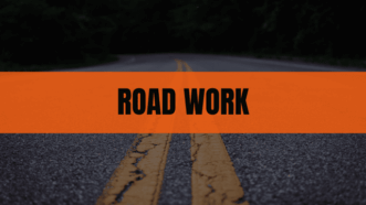 A two-lane road with double yellow lines, with an orange 'ROAD WORK' banner across the center.